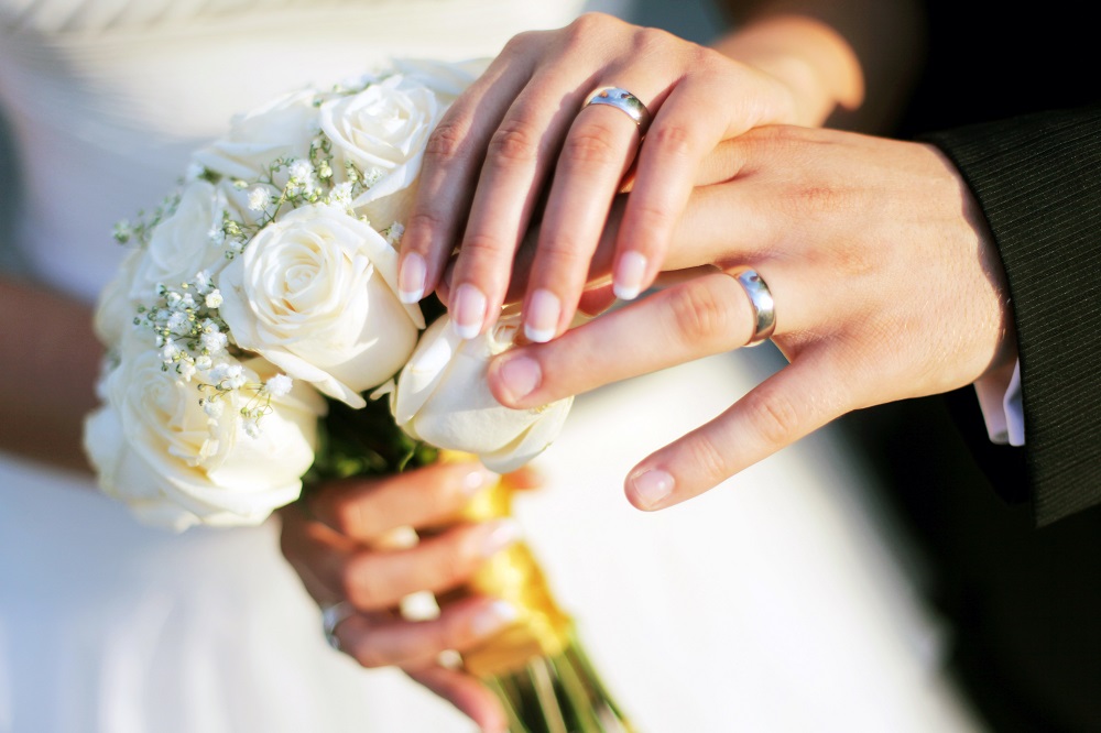Wedding rings, bouqet and hands holding